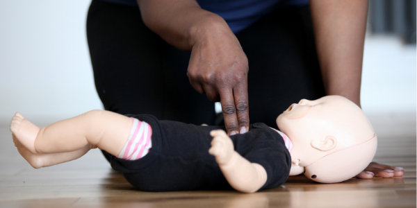 CPR being demonstrated on a first aid mannequin baby
